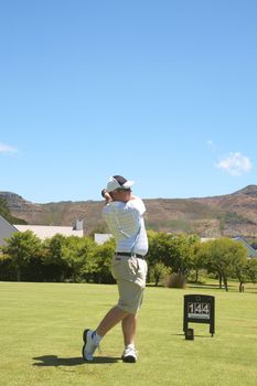 Young male golfer hitting the ball from the fairway on a beautiful summer day