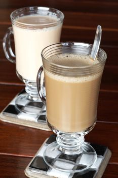 Closeup of coffee and tea served in glasses on dark wooden table in the morning