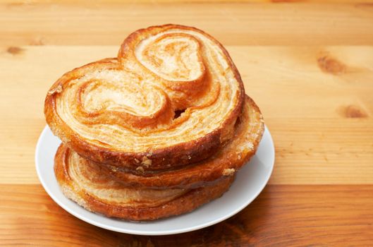 Palmier pastries on white saucer, shot on wooden board background