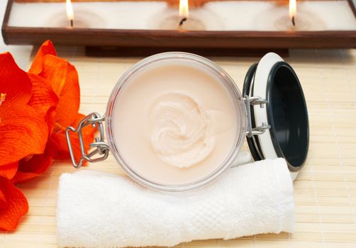 Relaxing spa scene with nourishing and exfoliating body scrub, white towel and candles in the background