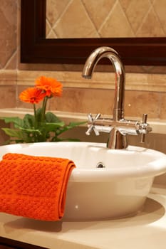 Beautiful sink in a bathroom with towel on it and a flower