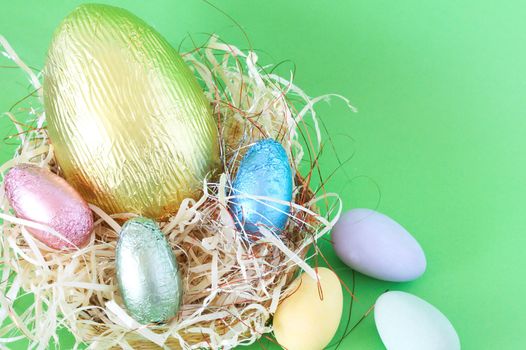 Chocolate Easter eggs in straw on green background