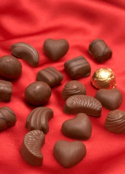 Assortment of Valentines chocolates on red silk background