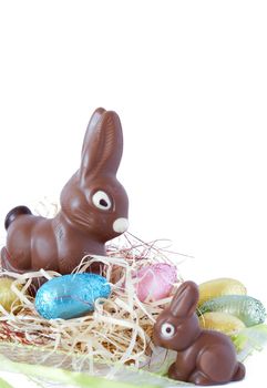 Assortment of chocolate Easter eggs wrapped in colorful paper with chocolate bunnies on straw