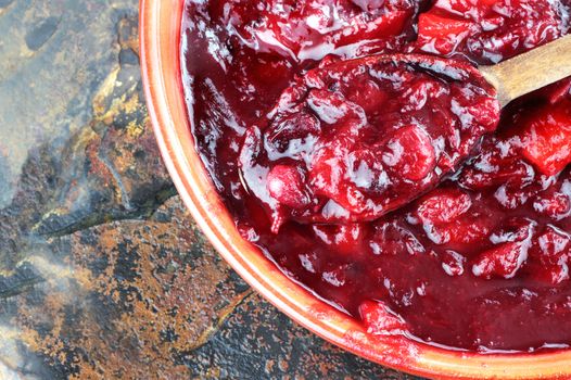 Fresh cranberry relish or sauce being stirred with a wooden spoon.