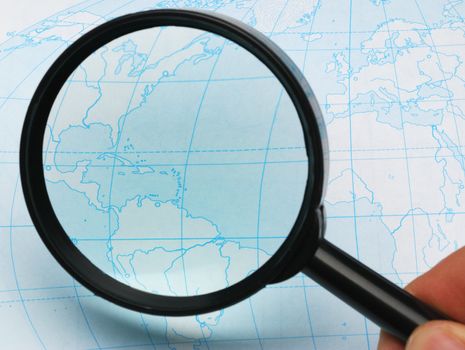 magnifier and card. Magnifying glass above a card of the world