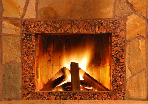 Fireplace. Flaring fire in a fireplace the reveted wild stone and a marble
