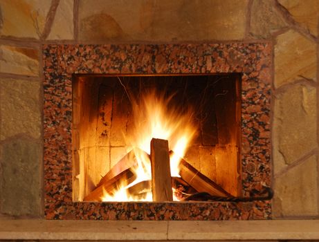 Fireplace. Flaring fire in a fireplace the reveted wild stone and a marble