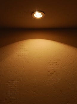 Light lamp. A textural wall shined by the lamp built in under a ceiling