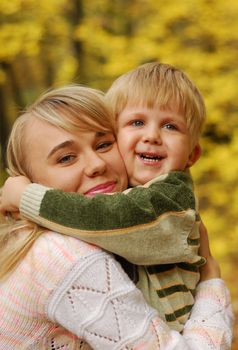 Mother with the child. On a background of yellow autumn foliage