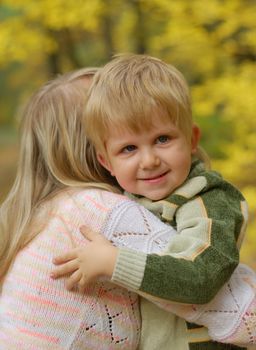 Mother with the child. On a background of yellow autumn foliage