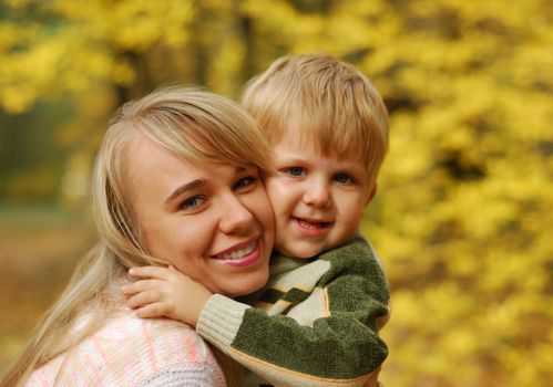 Mother with the child. On a background of yellow autumn foliage