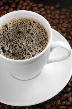 Cup of coffee with foam. A background with coffee grains and a white cup. A photo close up 