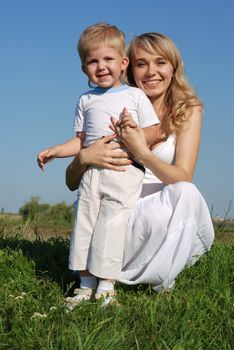 The mother and son. Happy people on a meadow with the clear blue sky