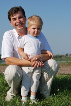 The father and son. Happy people on a meadow with the clear blue sky