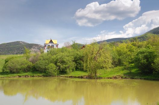 The house at lake. A cottage located in a valley, surrounded by mountains