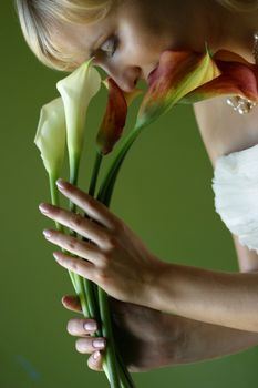 Five callas in hands of the beautiful bride on a green background