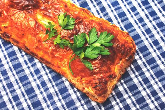 a pie from a puff test is decorated greenery of parsley on the checked serviette