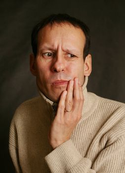 Adult man with toothache on dark background