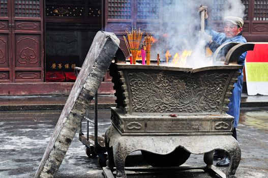 worker in Chinese buddhist shrine in the city of Shanghai China