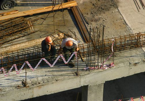 Two builders sit on a roof without work