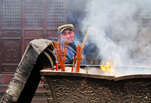 worker in Chinese buddhist shrine in the city of Shanghai China