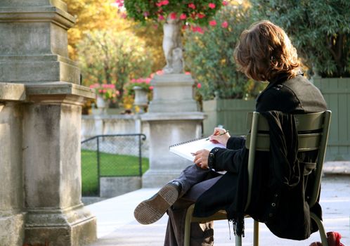 Girl drawing something in her sketchbook in the Luxembourg Garden, Paris