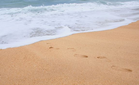 Footprints on the sand leading to the ocean