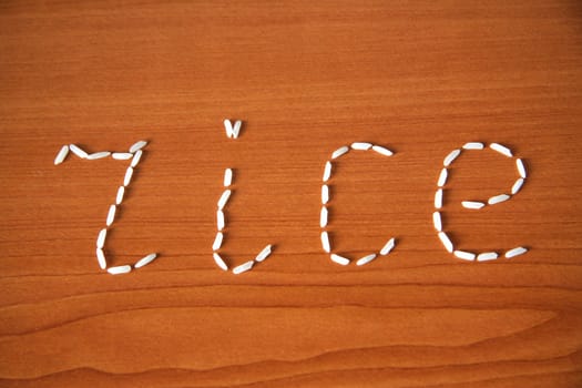 Rice grains in form of the word "rice" on the wooden background
