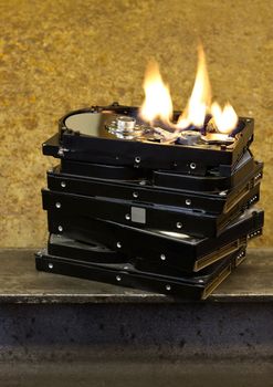 burning stack of hard drives in rusty background. the top drive is open and burning