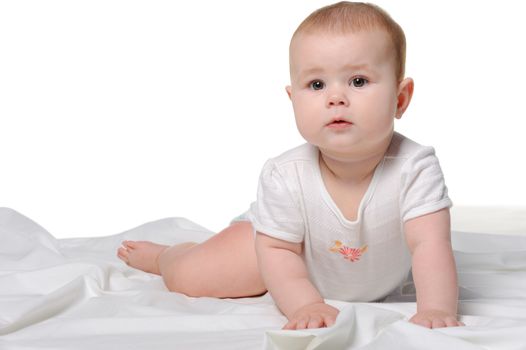 The baby on a bedsheet. Age of 8 months. It is isolated on a white background