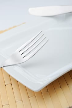 Fork and a knife laying on a plate. A photo close up