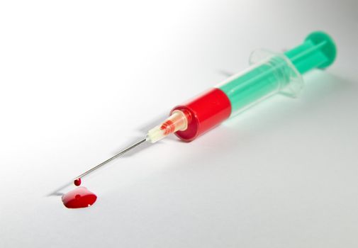 syringe laying on table filled with blood. Focus on needle