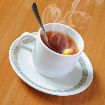 Tea. A white cup with tea and a lemon on a table