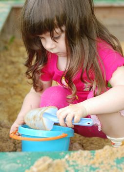 The girl playing to a sandbox. Caucasian the child, park of rest