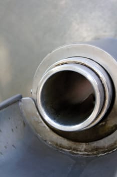 An outlet to an industrial pipe glistens in the sun
