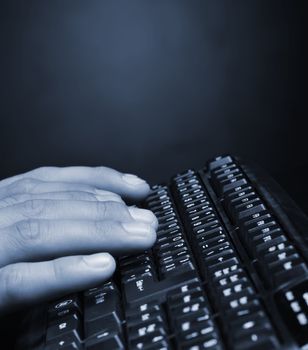 Hands above the keyboard. On a dark background, the black keyboard