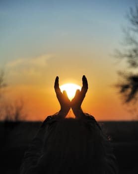 Decline in hands. A sunset on a background of the lifted female hands