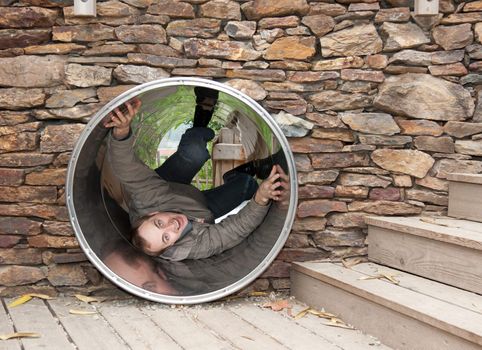 Lad creeps on steel pipe in stone wall