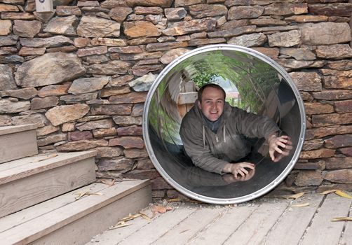 Lad creeps on steel pipe in stone wall