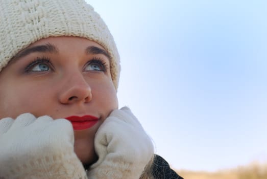 The girl in winter clothes. On a background of the blue sky