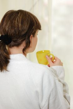 Morning coffee. The girl in a white dressing gown with a cup of coffee