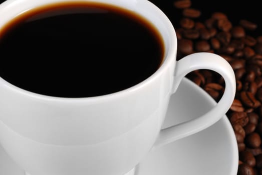 Cup of black coffee. A background with coffee grains and a white cup. A photo close up 