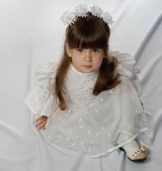 The girl in a white dress on white satin.Age 3 years