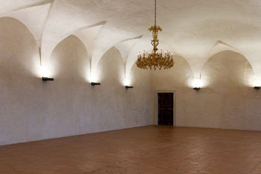 Room in the castle with a gold chandelier and candlesticks on the walls