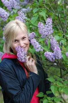 The pretty girl near a bush of a lilac. A smiling blonde