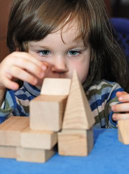 The child - architect. The girl collecting a design from wooden cubes.