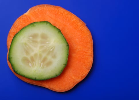 Carrots and cucumber on a dark blue background. Bright paints of a fresh product