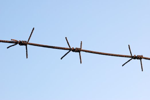 The barbed wire is isolated on a background of the blue sky