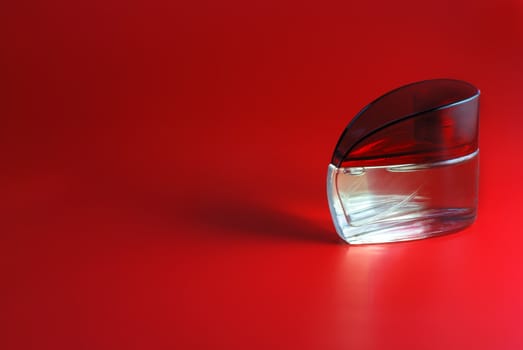 perfume. A bottle perfume on a red background with effective illumination